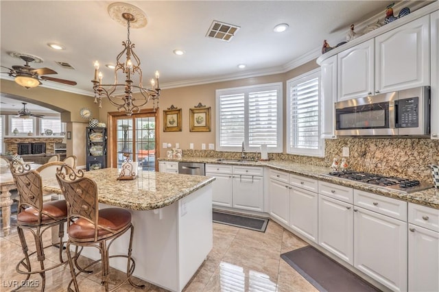 56 Ancient Hills Ln, Henderson, NV 89074 - kitchen featuring stainless steel appliances, ceiling fan, a breakfast bar, crown molding, and a chandelier