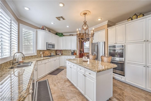 56 Ancient Hills Ln, Henderson, NV 89074 - kitchen featuring stainless steel appliances, a center island, crown molding, a chandelier, and decorative backsplash