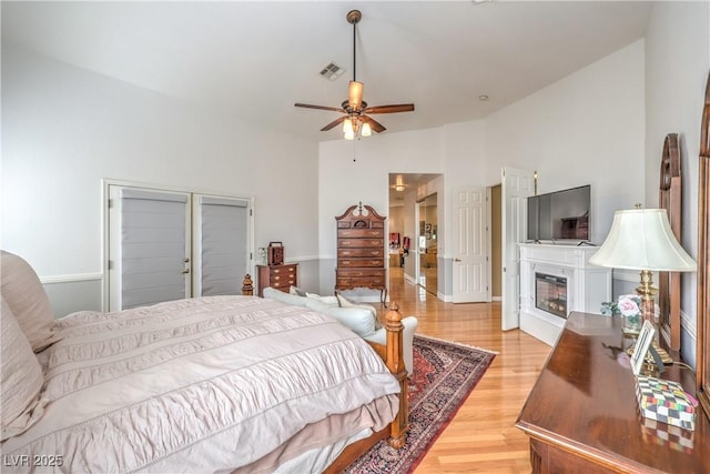 56 Ancient Hills Ln, Henderson, NV 89074 - bedroom with light wood-style flooring, a glass covered fireplace, lofted ceiling, and a ceiling fan