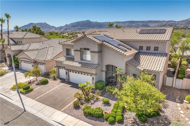 56 Ancient Hills Ln, Henderson, NV 89074 - mediterranean / spanish home featuring stucco siding, a mountain view, a tiled roof, solar panels, and a garage
