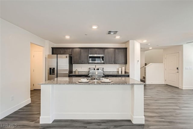 2670 Mango Light Ave, North Las Vegas, NV 89086 - kitchen featuring stainless steel appliances, dark wood finished floors, a kitchen island with sink, dark brown cabinetry, and light stone counters