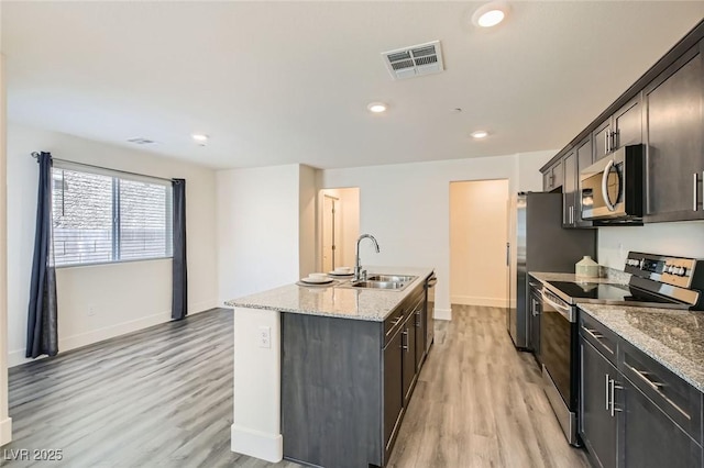 2670 Mango Light Ave, North Las Vegas, NV 89086 - kitchen with stainless steel appliances, a center island with sink, light wood finished floors, light stone countertops, and recessed lighting
