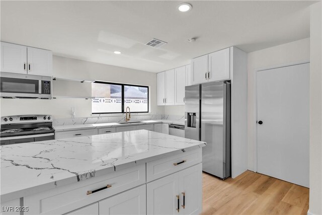 6204 Robin Hood Cir, Las Vegas, NV 89108 - kitchen featuring appliances with stainless steel finishes, recessed lighting, white cabinets, light stone countertops, and light wood-style flooring