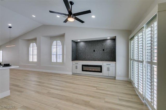 1844 Grand Prairie Ave, North Las Vegas, NV 89032 - unfurnished living room with vaulted ceiling, a ceiling fan, light wood-style flooring, and a glass covered fireplace