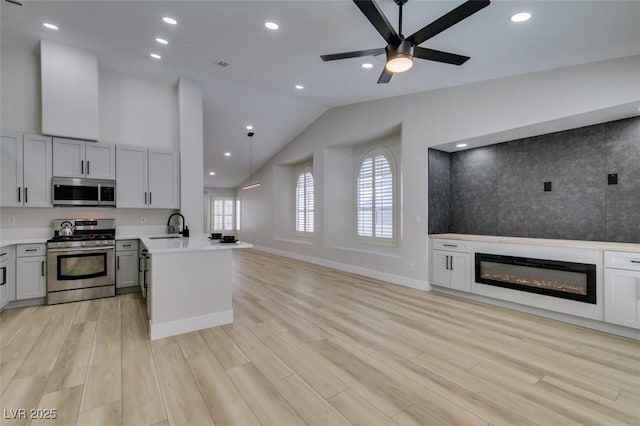 1844 Grand Prairie Ave, North Las Vegas, NV 89032 - kitchen with appliances with stainless steel finishes, open floor plan, vaulted ceiling, light countertops, and a glass covered fireplace