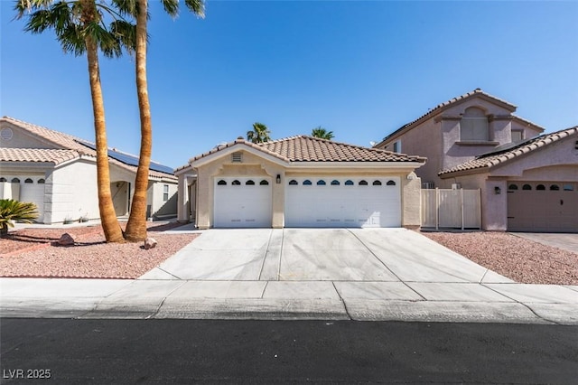 1844 Grand Prairie Ave, North Las Vegas, NV 89032 - mediterranean / spanish home with driveway, a tile roof, an attached garage, stucco siding, and roof mounted solar panels