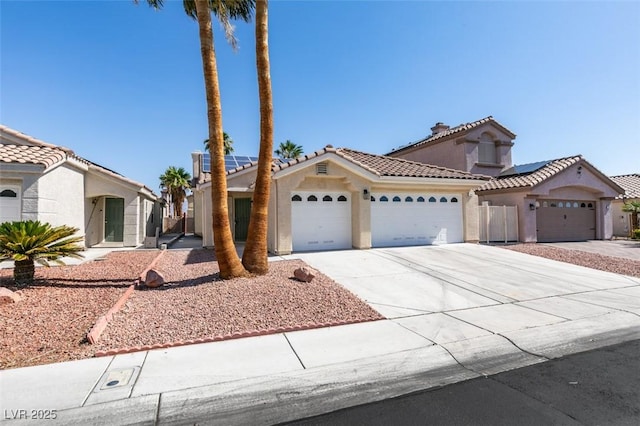 1844 Grand Prairie Ave, North Las Vegas, NV 89032 - mediterranean / spanish-style house with a garage, concrete driveway, stucco siding, a tiled roof, and roof mounted solar panels