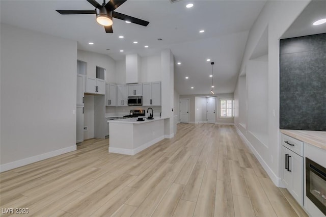 1844 Grand Prairie Ave, North Las Vegas, NV 89032 - kitchen with stainless steel microwave, open floor plan, stove, a ceiling fan, and light wood-style flooring