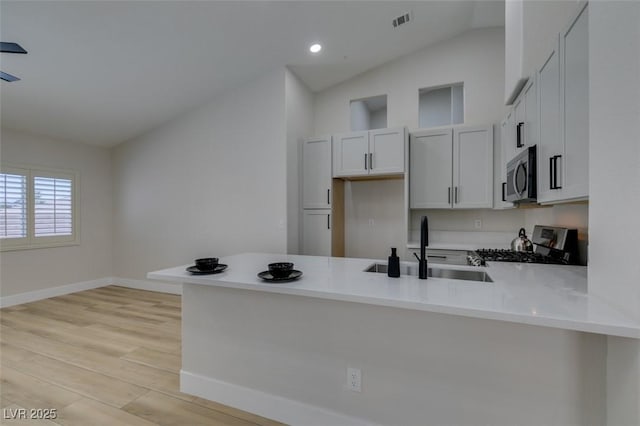 1844 Grand Prairie Ave, North Las Vegas, NV 89032 - kitchen featuring range with gas cooktop, stainless steel microwave, a peninsula, light countertops, and vaulted ceiling