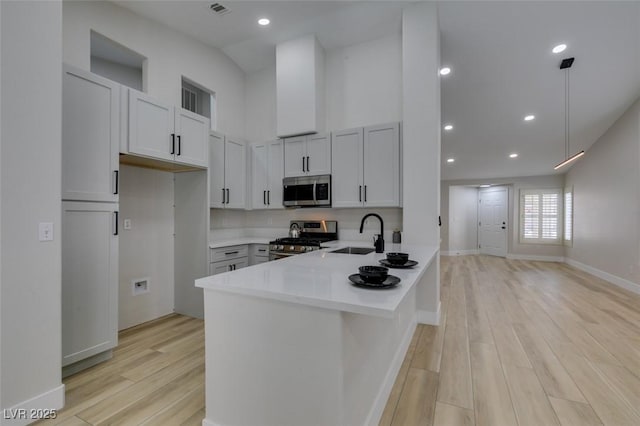 1844 Grand Prairie Ave, North Las Vegas, NV 89032 - kitchen featuring stainless steel appliances, a peninsula, light countertops, light wood finished floors, and recessed lighting