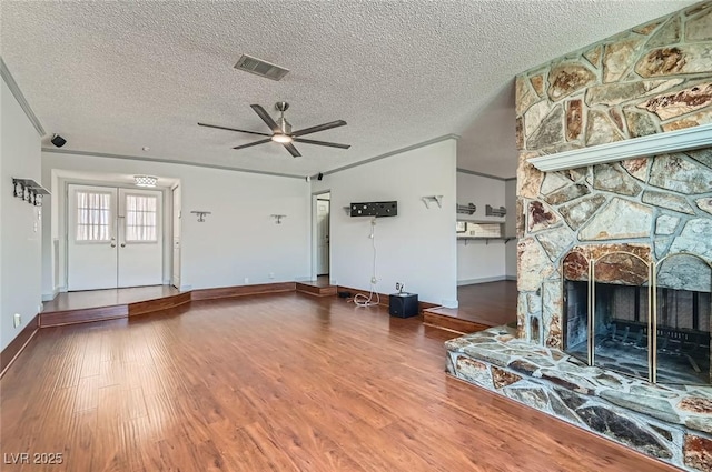 7704 Peacock Ave, Las Vegas, NV 89145 - unfurnished living room featuring wood finished floors, a ceiling fan, a textured ceiling, and a stone fireplace