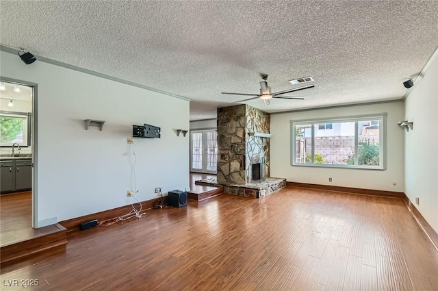 7704 Peacock Ave, Las Vegas, NV 89145 - unfurnished living room with wood finished floors, ceiling fan, a fireplace, a textured ceiling, and crown molding