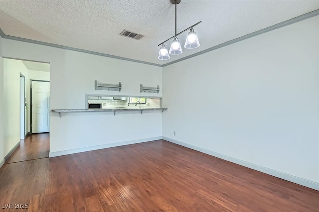 7704 Peacock Ave, Las Vegas, NV 89145 - kitchen with dark wood finished floors, a breakfast bar, a textured ceiling, a peninsula, and ornamental molding