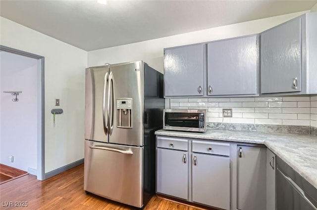 7704 Peacock Ave, Las Vegas, NV 89145 - kitchen featuring stainless steel appliances, gray cabinetry, tasteful backsplash, and light wood-style flooring