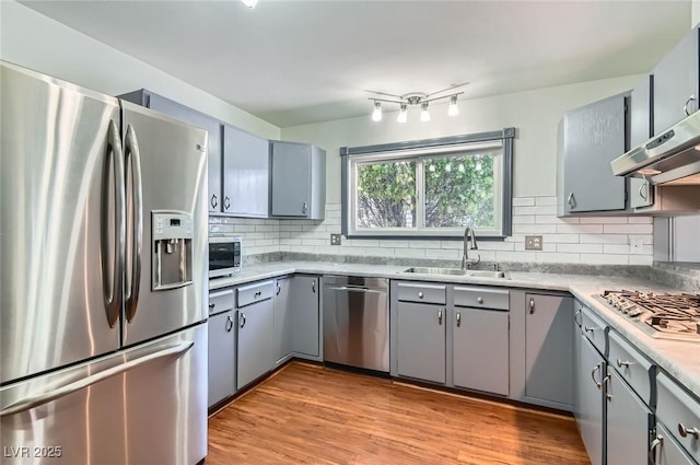 7704 Peacock Ave, Las Vegas, NV 89145 - kitchen with stainless steel appliances, gray cabinets, wall chimney range hood, decorative backsplash, and light wood-style flooring