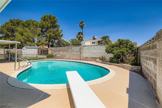 7704 Peacock Ave, Las Vegas, NV 89145 - view of pool with a fenced backyard, a patio area, a diving board, and an outbuilding