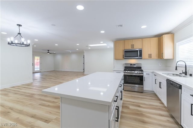 1571 Pawnee Dr, Las Vegas, NV 89169 - kitchen featuring stainless steel appliances, light countertops, a center island, a ceiling fan, and light wood-type flooring