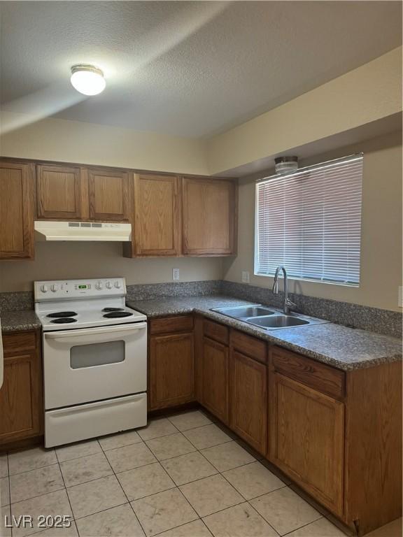 3420 Mercury St Unit B, North Las Vegas, NV 89030 - kitchen with white electric stove, under cabinet range hood, brown cabinetry, dark countertops, and light tile patterned floors