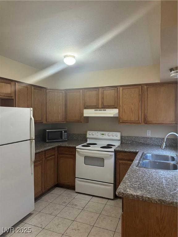 3420 Mercury St Unit B, North Las Vegas, NV 89030 - kitchen with white appliances, under cabinet range hood, dark countertops, brown cabinetry, and light tile patterned flooring
