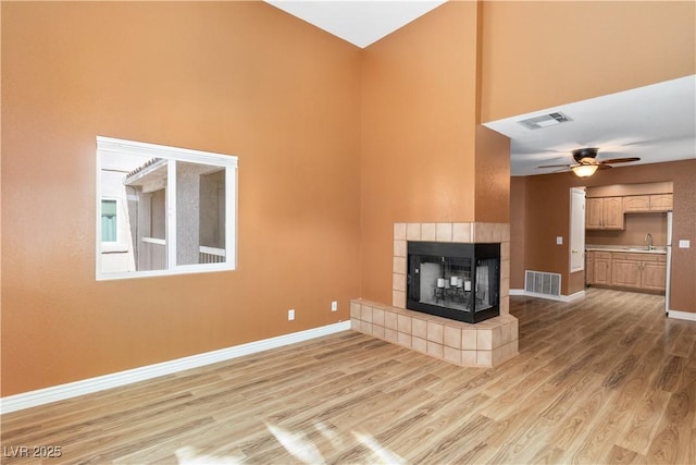 1948 Las Palmas Ln Unit 277, Laughlin, NV 89029 - unfurnished living room featuring light wood finished floors, a ceiling fan, a fireplace, and a towering ceiling