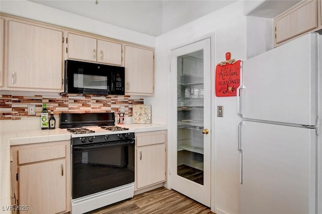 6201 E Lake Mead Blvd Unit 223, Las Vegas, NV 89156 - kitchen with freestanding refrigerator, range with gas cooktop, tile counters, black microwave, and decorative backsplash