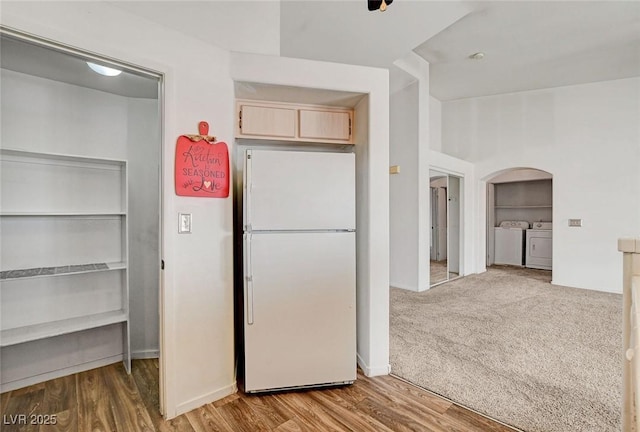 6201 E Lake Mead Blvd Unit 223, Las Vegas, NV 89156 - kitchen with washing machine and clothes dryer, freestanding refrigerator, light brown cabinetry, arched walkways, and wood finished floors