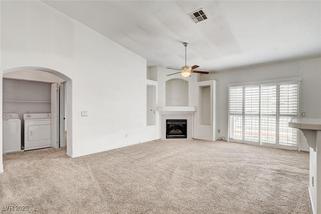 6201 E Lake Mead Blvd Unit 223, Las Vegas, NV 89156 - unfurnished living room with washer and dryer, ceiling fan, carpet flooring, arched walkways, and a glass covered fireplace