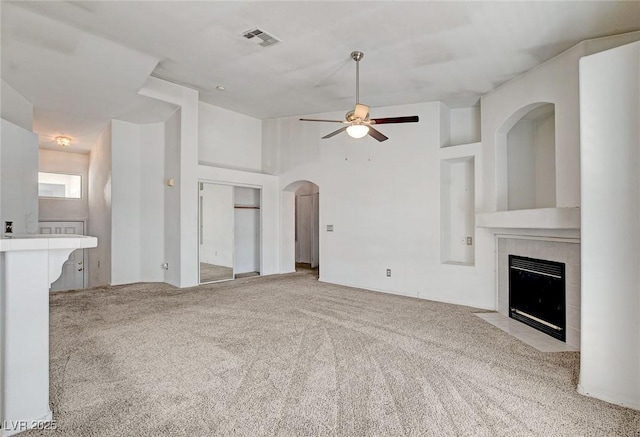 6201 E Lake Mead Blvd Unit 223, Las Vegas, NV 89156 - unfurnished living room featuring a tiled fireplace, ceiling fan, carpet floors, and arched walkways