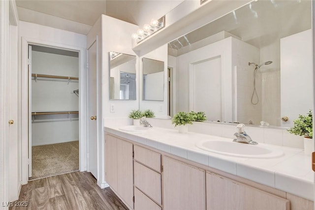 6201 E Lake Mead Blvd Unit 223, Las Vegas, NV 89156 - bathroom featuring a shower, double vanity, wood finished floors, and a spacious closet