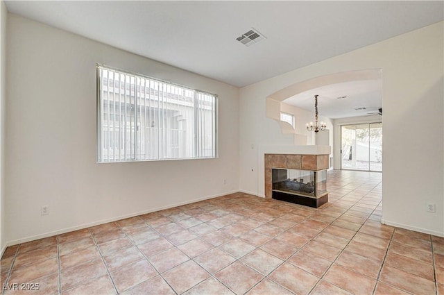 10612 Primrose Arbor Ave, Las Vegas, NV 89144 - unfurnished living room with a chandelier, arched walkways, and a tile fireplace