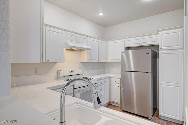 10612 Primrose Arbor Ave, Las Vegas, NV 89144 - kitchen with freestanding refrigerator, under cabinet range hood, white range with gas cooktop, white cabinets, and recessed lighting