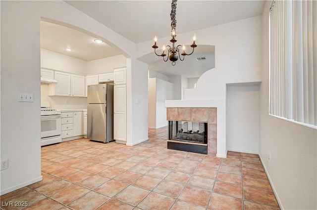10612 Primrose Arbor Ave, Las Vegas, NV 89144 - kitchen featuring white range with gas stovetop, freestanding refrigerator, a chandelier, arched walkways, and white cabinetry