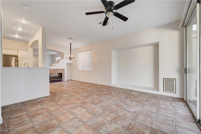10612 Primrose Arbor Ave, Las Vegas, NV 89144 - unfurnished living room with ceiling fan, a fireplace, arched walkways, and a chandelier