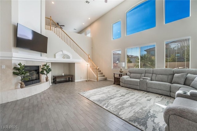 8929 Glenistar Gate Ave, Las Vegas, NV 89143 - living room with stairway, a towering ceiling, wood finished floors, a tiled fireplace, and recessed lighting