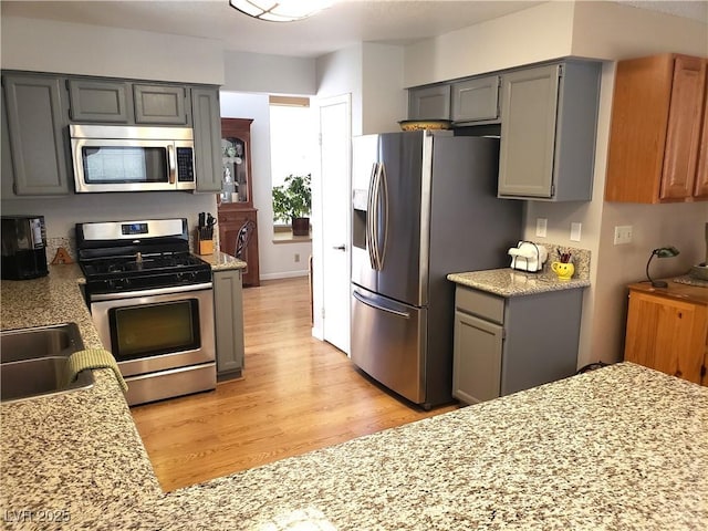 4816 Fiesta Lakes St, Las Vegas, NV 89130 - kitchen featuring stainless steel appliances, gray cabinetry, and light wood finished floors