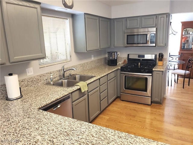 4816 Fiesta Lakes St, Las Vegas, NV 89130 - kitchen featuring stainless steel appliances, gray cabinetry, light wood-style floors, and light stone counters