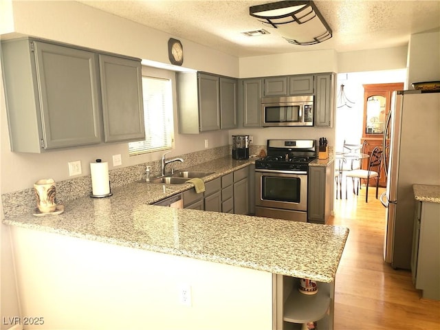 4816 Fiesta Lakes St, Las Vegas, NV 89130 - kitchen featuring appliances with stainless steel finishes, gray cabinets, a textured ceiling, a peninsula, and light wood-style flooring