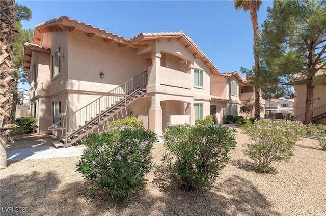 350 S Durango Dr Unit 202, Las Vegas, NV 89145 - view of side of home featuring stairs, a tile roof, and stucco siding