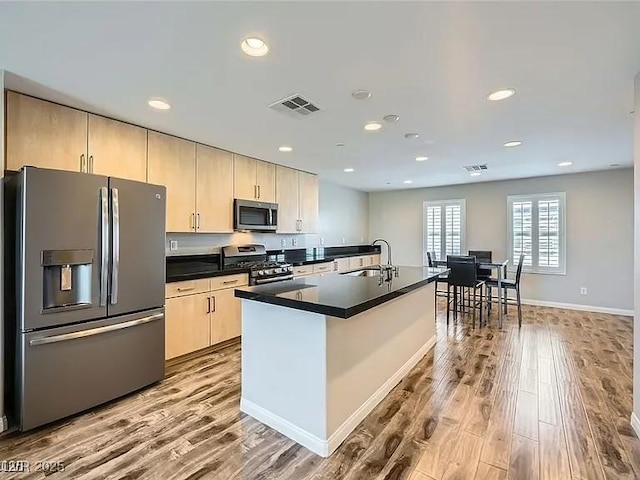 9050 W Tropicana Ave Unit 1015, Las Vegas, NV 89147 - kitchen featuring stainless steel appliances, wood finished floors, light brown cabinets, dark countertops, and recessed lighting