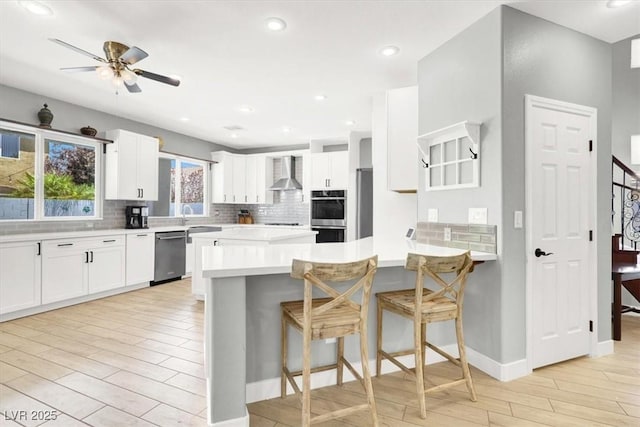 7816 Red Leaf Dr, Las Vegas, NV 89131 - kitchen with appliances with stainless steel finishes, wall chimney exhaust hood, decorative backsplash, light wood-style floors, and ceiling fan