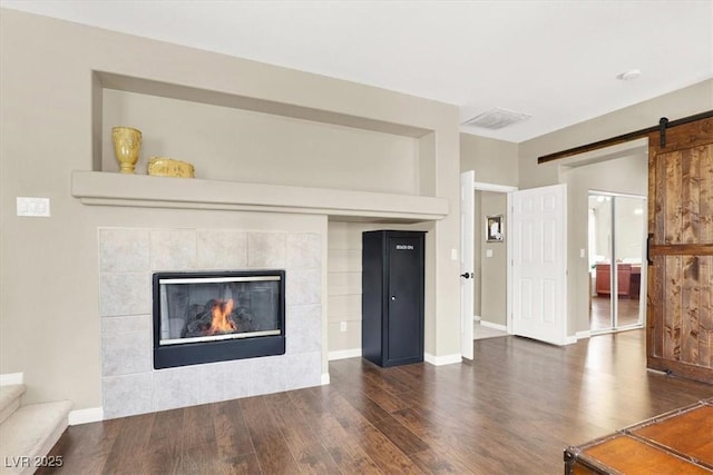 7816 Red Leaf Dr, Las Vegas, NV 89131 - unfurnished living room featuring wood finished floors, a barn door, and a tiled fireplace