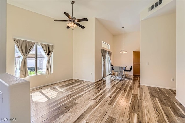 8805 Jeffreys St Unit 1089, Las Vegas, NV 89123 - unfurnished living room featuring a towering ceiling, wood finished floors, a ceiling fan, and a chandelier