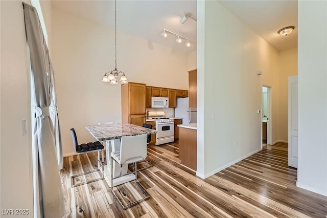 8805 Jeffreys St Unit 1089, Las Vegas, NV 89123 - kitchen with white appliances, a high ceiling, a chandelier, wood finished floors, and brown cabinets