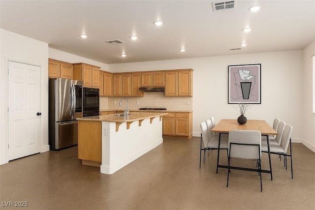520 Ivy Spring St, Las Vegas, NV 89138 - kitchen featuring smart refrigerator, cooktop, a breakfast bar, a kitchen island with sink, and decorative backsplash