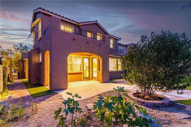 520 Ivy Spring St, Las Vegas, NV 89138 - back of property at dusk featuring stucco siding, a tiled roof, and a patio