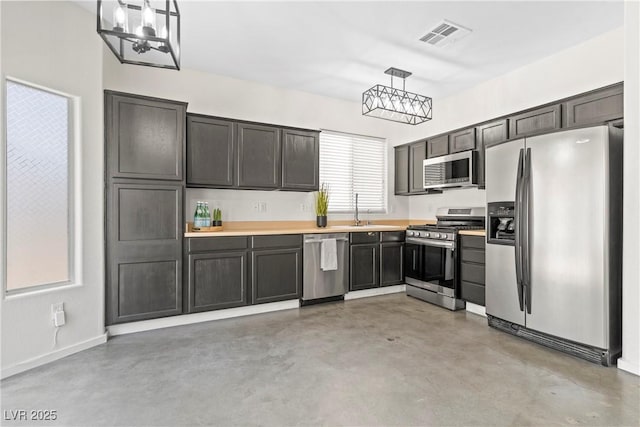 9420 Plover Falls Ave, Las Vegas, NV 89149 - kitchen with stainless steel appliances, concrete floors, hanging light fixtures, light countertops, and a chandelier