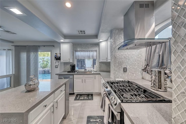 895 Beartooth Falls Ct, Henderson, NV 89052 - kitchen featuring island exhaust hood, stainless steel appliances, white cabinets, decorative backsplash, and light stone countertops