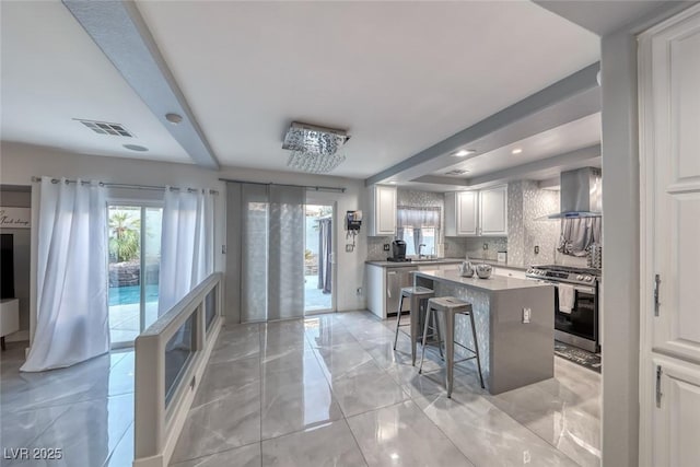 895 Beartooth Falls Ct, Henderson, NV 89052 - kitchen featuring wall chimney exhaust hood, appliances with stainless steel finishes, a kitchen island, decorative backsplash, and white cabinetry