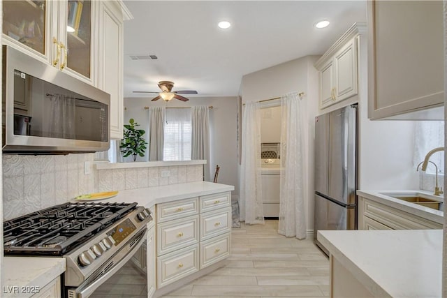 9000 Las Vegas Blvd Unit 2060, Las Vegas, NV 89123 - kitchen with stainless steel appliances, a ceiling fan, decorative backsplash, light countertops, and glass insert cabinets