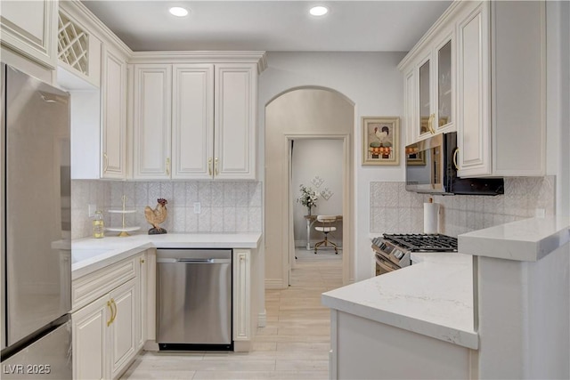 9000 Las Vegas Blvd Unit 2060, Las Vegas, NV 89123 - kitchen featuring stainless steel appliances, arched walkways, backsplash, glass insert cabinets, and light stone counters